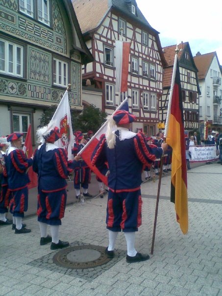 German men in traditional costume with an old style German village in the background