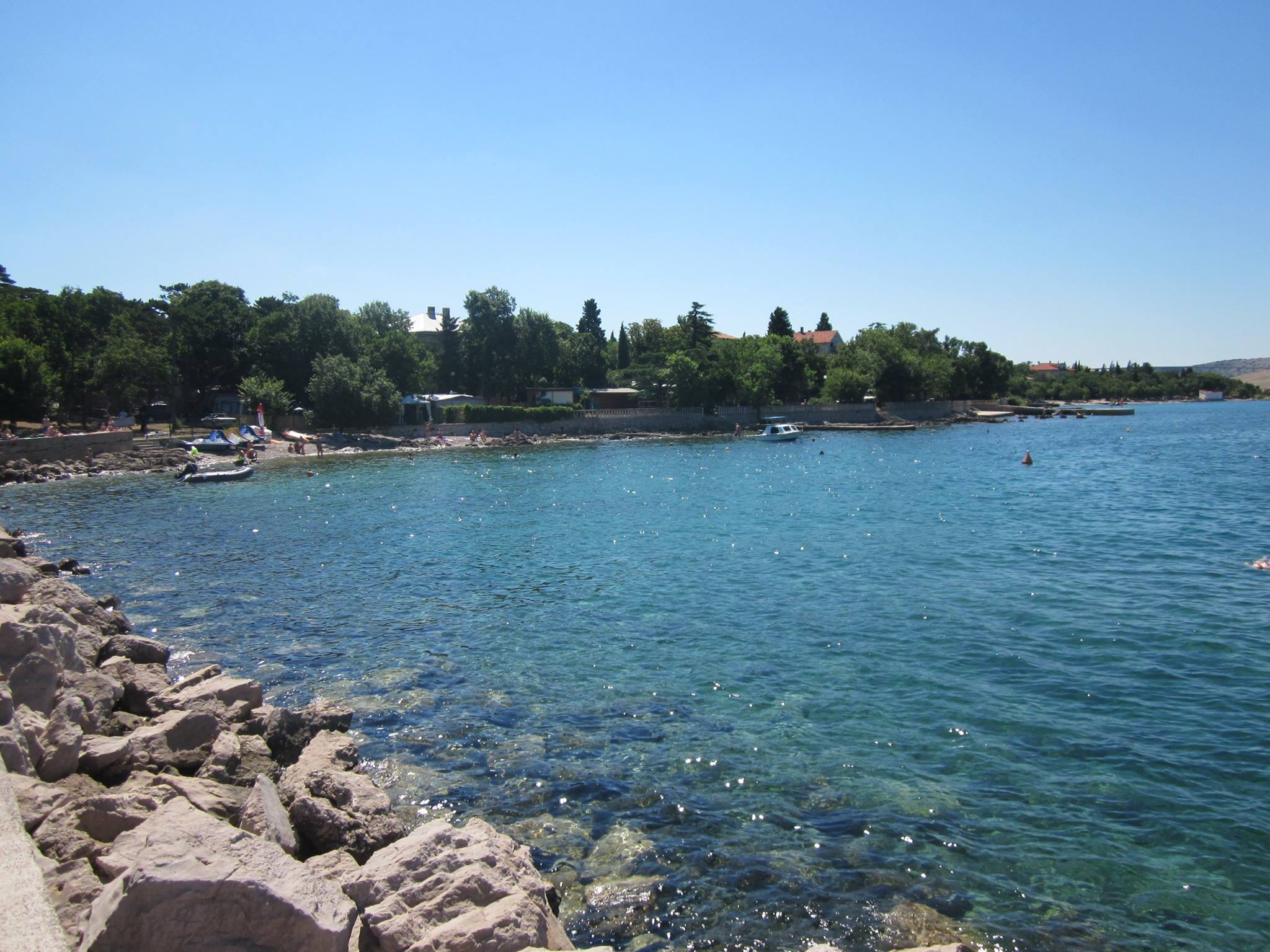 A view of the sea in Croatia, with rocks in the foreground and trees in the background